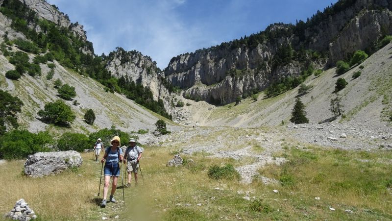 Randonneurs au pied d'une grande combe rocheuse