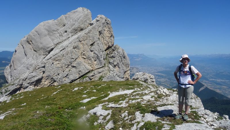 Randonneuse au pied d'un grand rocher, Grenoble en contrebas