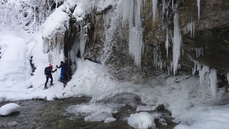 Cascade de glace et raquettistes au bord du torrent