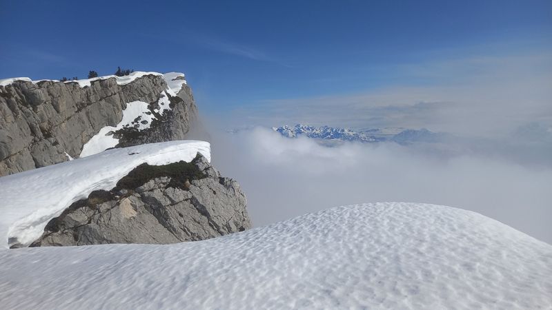Falaise enneigée au-dessus d'une mer de nuages