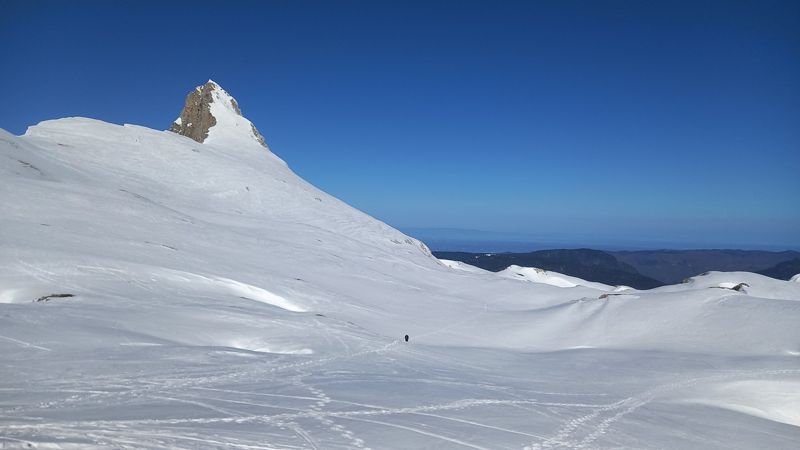 Aiguille rocheuse et grande combe enneigée