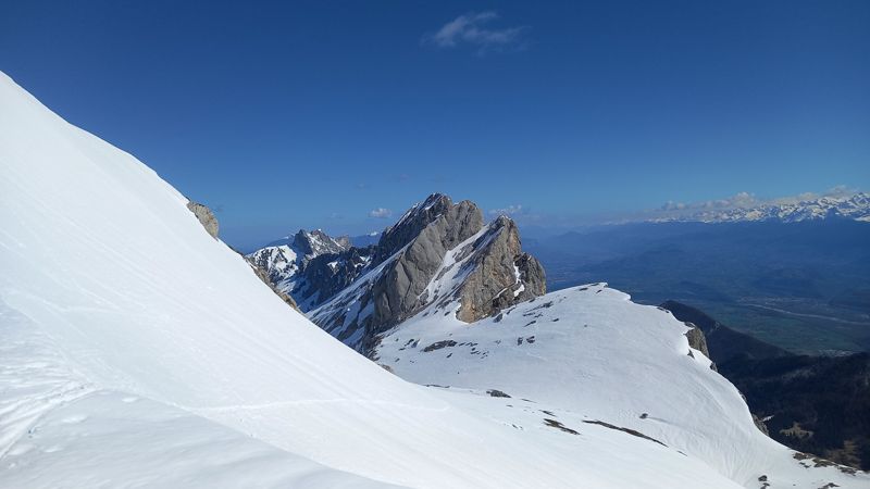 Aiguilles rocheuses enneigées face aux Alpes